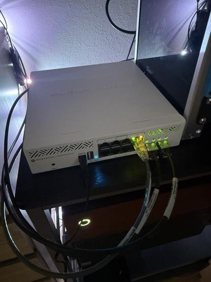 A network switch with three cables connected and LEDs showing activity on those ports.